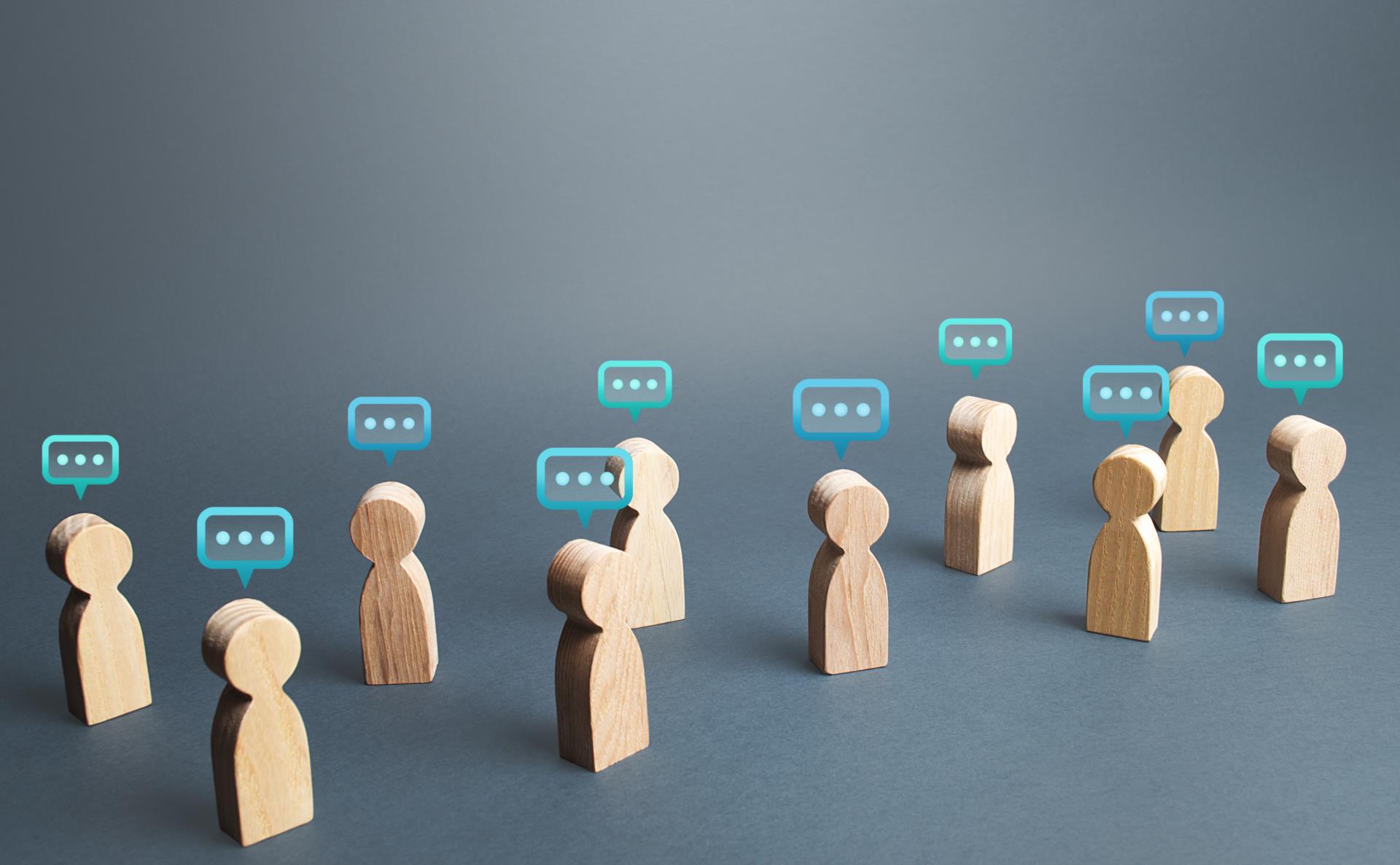 Wooden figurines conversating with speech bubbles smaller