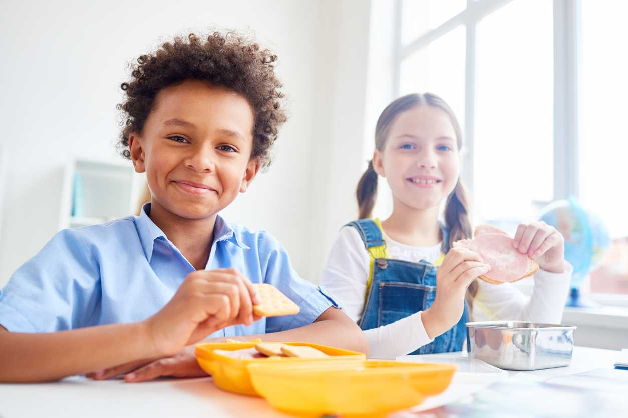 Tween boy and girl eating school lunch