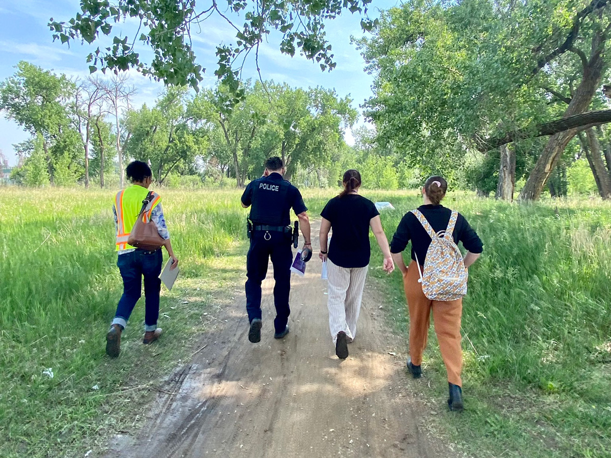 City staff, a Loveland Police officer, and a co-responder from SummitStone Health Partners walk toward an unauthorized encampment on June 17 to issue the first unauthorized encampment ban notice in King’s Crossing.