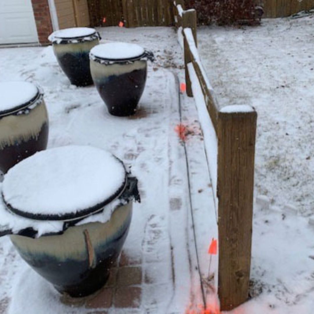 Several orange markings indicate the path of a temporary fiber line placed on top of snow in a yard.