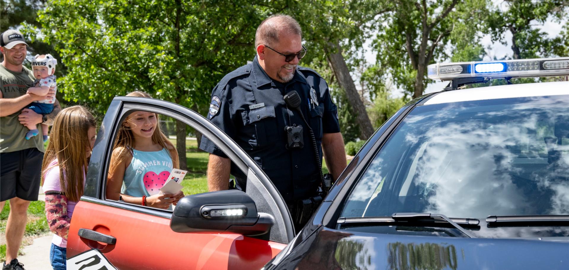 officer looking at police car with kids