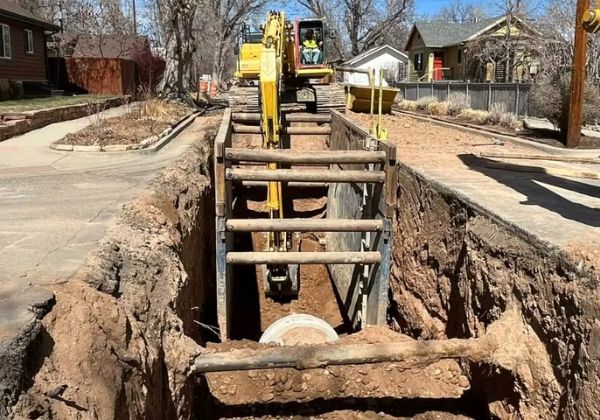 A large portion of road is under construction. There are several large pieces of machinery in the background.