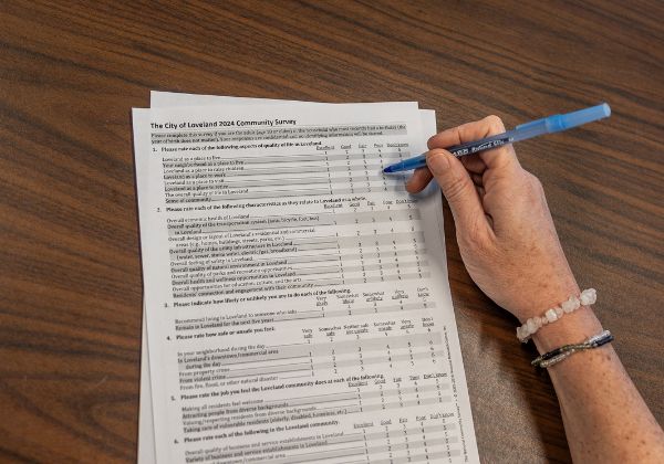 A person filling out the City of Loveland 2024 Community Survey with a blue pen.