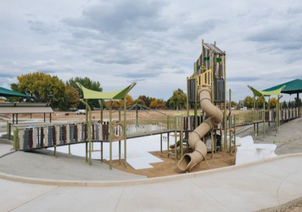 Playground structure with slides and shaded areas under a partly cloudy sky.